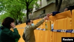 上海封城后居民从围栏上递送食用油。（2022年4月13日）