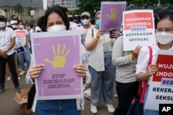 Aktivis memegang poster bertuliskan "Hentikan kekerasan seksual" dan "Bebaskan Indonesia dari kekerasan seksual", saat demonstrasi memperingati Hari Perempuan Internasional di Jakarta, Selasa, 8 Maret 2022. (Foto: AP)