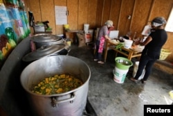 Florinda Salazar and Elena Rodriguez prepare food in the soup kitchen where they work in Pamplona Alta, a low-income neighborhood in Lima, Peru April 11, 2022. (REUTERS/Daniel Becerril)