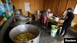 Florinda Salazar dan Elena Rodriguez menyiapkan makanan di dapur sup tempat mereka bekerja di Pamplona Alta, sebuah wilayah miskin di Lima, Peru, pada 11 April 2022. (Foto: Reuters/Daniel Becerril)