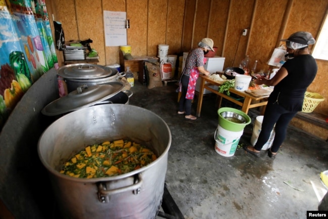 Florinda Salazar and Elena Rodriguez prepare food in the soup kitchen where they work in Pamplona Alta, a low-income neighborhood in Lima, Peru April 11, 2022. (REUTERS/Daniel Becerril)