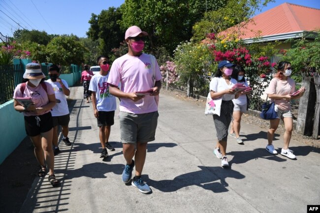 Sukarelawan untuk capres oposisi dan wapres saat ini, Leni Robredo, membagikan brosur kepada warga selama kampanye dari rumah ke rumah di kota Pasuquin, provinsi Ilocos Norte, Filipina, 26 Maret 2022. (Foto; Ted ALJIBE / AFP)
