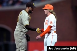 San Diego Padres player Eric Hosmer congratulates San Francisco Giants first base coach Alyssa Nakken at a game on Tuesday, April 12, 2022. (AP Photo/Jed Jacobsohn)