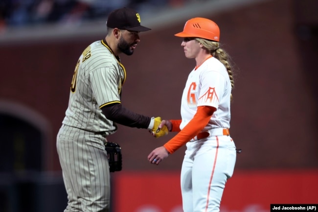 San Diego Padres player Eric Hosmer congratulates San Francisco Giants first base coach Alyssa Nakken at a game on Tuesday, April 12, 2022. (AP Photo/Jed Jacobsohn)