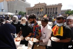 Warga Sri Lanka menandai awal tahun baru Sinhala dan Tamil dengan berbagi makanan tradisonal di tengah aksi protes anti-pemerintah di dekat kantor presiden di Kolombo, Sri Lanka, Kamis, 14 April 2022. (AP/Eranga Jayawardena)