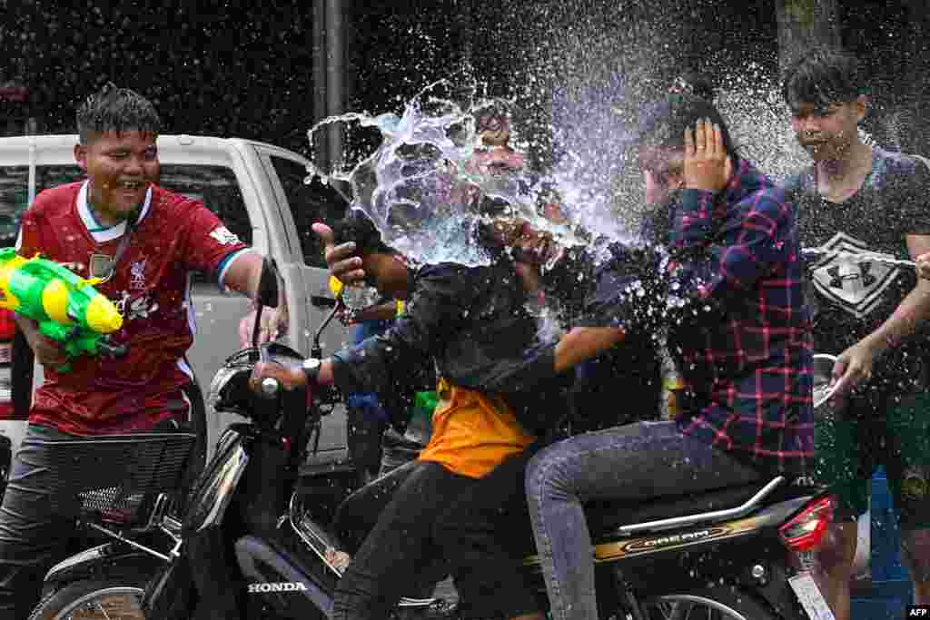 People use water guns to spray water at passing motorists along a street during Khmer New Year celebrations in Siem Reap province on April 14, 2022.