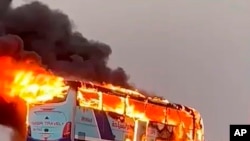 A tourist bus burns after it collided with a truck on a highway 55 kilometers (34 miles) south of Aswan, southern Egypt, April 13, 2022. 