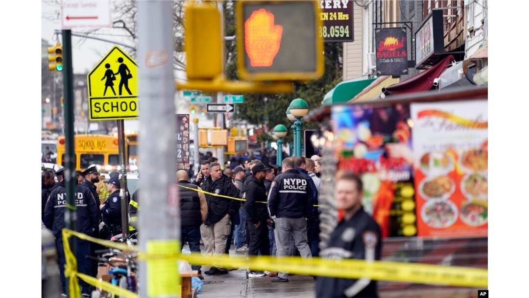 Polisi New York (NYPD) berkumpul di pintu masuk halte kereta bawah tanah di wilayah Brooklyn, New York, Selasa, 12 April 2022. Lima orang ditembak pria tak dikenal di sebuah stasiun kereta bawah tanah di Brooklyn, New York. (AP/John Minchillo)