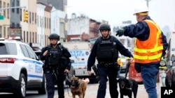 Des policiers accompagnés de chiens renifleurs de bombes surveillent une zone après une fusillade dans une rame de métro, mardi 12 avril 2022, dans le quartier de Brooklyn à New York. 