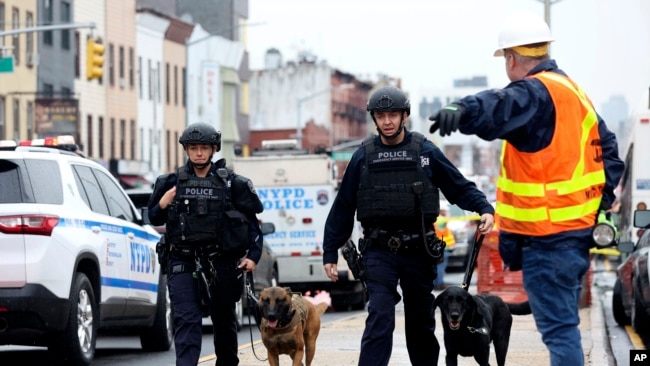 FILE - Officers with bomb-sniffing dogs look over the area after a shooting on a subway train, April. 12, 2022, in the Brooklyn borough of New York.