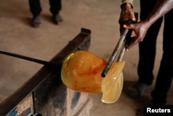 Michael Tetteh dibantu stafnya, memproduksi barang pecah belah di bengkel kerjanya di Krobo Odumase, Ghana 15 Maret 2022. (REUTERS/Francis Kokoroko)