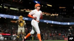 San Francisco Giants first base coach Alyssa Nakken runs to get in position, near San Diego Padres catcher Austin Nola, left, during the third inning of a baseball game in San Francisco, Tuesday, April 12, 2022.