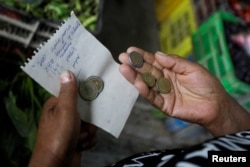 Elena Rodriguez carries a list of produce and money to make purchases for the soup kitchen where she works in Pamplona Alta in Lima, Peru April 11, 2022. (REUTERS/Daniel Becerril)