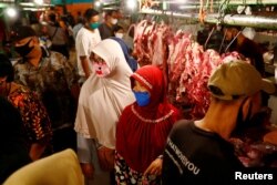 Orang-orang yang memakai masker pelindung wajah membeli daging untuk membuat makanan tradisional menjelang perayaan Idul Fitri di pasar tradisional di tengah wabah COVID-19 di Jakarta, 22 Mei 2020. (Foto: REUTERS/Ajeng Dinar Ulfiana)