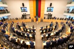 Members of Lithuanian parliament give Ukraine President Volodymyr Zelenskyy a standing ovation before he speaks in a virtual address to Lithuanian parliament in Vilnius, Lithuania, April 12, 2022.