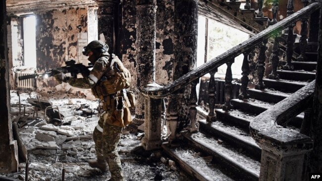 A Russian soldier patrols at the Mariupol drama theater that was bombed last March 16, in Mariupol, as Russian troops intensify a campaign to take the strategic port city, April 12, 2022.