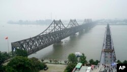 FILE - In this Sept. 9, 2017, photo, visitors walk across the Yalu River Broken Bridge, right, next to the Friendship Bridge connecting China and North Korea in Dandong in northeastern China's Liaoning province.