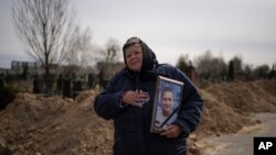 乌克兰基辅郊区，一名妇女手捧32岁的德米特罗·斯特菲延科的肖像。他是一名在俄军入侵中丧生的当地平民。(2022年4月12日）