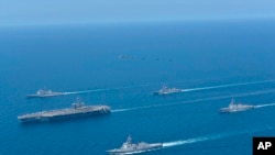 资料照：这张由日本海上自卫队提供的照片显示，2022年4月12日，在日本海举行的美日双边演习中，林肯号航母(左)和金刚号护卫舰(前)编队航行。(美联社）
