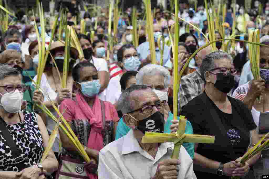 Un hombre carga una cruz hecha con palmeras que la hermandad de Los Palmeros recolectó previamente en el Cerro El Ávila, mientras asistía a una misa de Domingo de Ramos que marca el inicio de la Semana Santa, en la plaza Bolívar del municipio de Chacao en Caracas, el 10 de abril. 2022.