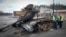 Road workers examine a destroyed Russian tank on the highway to Kyiv, Ukraine, April 11, 2022.