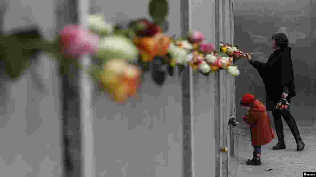 Une mère et sa jeune fille posent des roses au mémorial du mur de Berlin à Bernauer Strasse, pendant une cérémonie marquant le 25ème anniversaire de la chute du mur de Berlin à Berlin, le 9 novembre 2014.