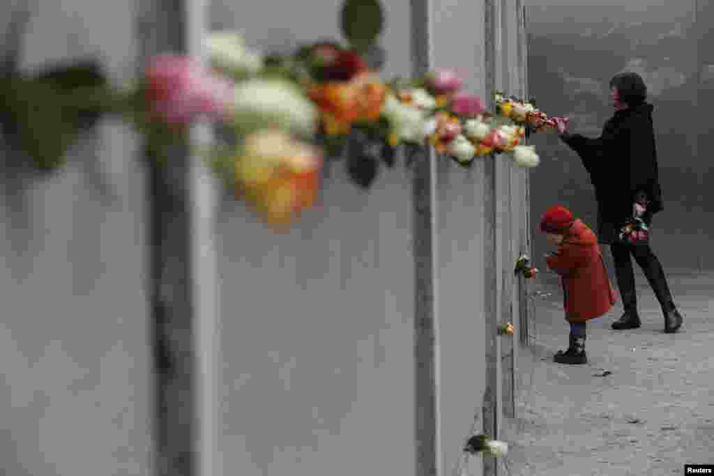 A mother and young daughter place roses at the Berlin Wall memorial in Bernauer Strasse, during a ceremony marking the 25th anniversary of the fall of the Berlin Wall in Berlin, Nov. 9, 2014. 