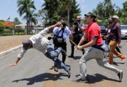 A supporter of Venezuela's President Nicolas Maduro fights with an opposition leader Juan Guaido's supporter outside Venezuelan embassy in Brasilia, Brazil, Nov. 13, 2019.