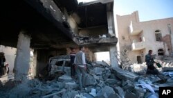 People inspect the wreckage of buildings that were damaged by Saudi-led coalition airstrikes, in Sanaa, Yemen, Jan. 18, 2022.