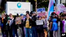 FILE - Transgender rights supporters protest at a hospital in Seattle, Washington, after it postponed some gender-affirming surgeries for minors after an executive order by President Donald Trump, Feb. 9, 2025. A federal judge extended a nationwide block Tuesday on the orders.