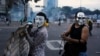 Manifestantes anti-governo mascarados transportam um escudo improvisado durante os confrontos com a polícia na Praça Altamira, em Caracas, Fev. 27, 2014. 