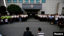 Anggota keluarga korban yang selamat dari bencana feri Sewol duduk di depan sebuah gedung tempat kru ditahan, setelah menghadiri kesaksian di pengadilan lokal di Gwangju, 10 Juni 2014.