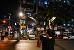 A woman clatters pans to make noise after calls for protest went out on social media in Yangon as Myanmar's ousted leader Aung San Suu Kyi was formally charged two days after she was detained in a military coup.