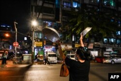 A woman clatters pans to make noise after calls for protest went out on social media in Yangon as Myanmar's ousted leader Aung San Suu Kyi was formally charged two days after she was detained in a military coup.