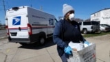 A United States postal worker outfitted with gloves and a mask makes a delivery in Warren, Michigan, April 2, 2020. The U.S. Postal Service has suspended mail to 22 countries due to the COVID-19 pandemic. 