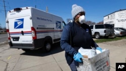 A United States postal worker outfitted with gloves and a mask makes a delivery in Warren, Michigan, April 2, 2020. The U.S. Postal Service has suspended mail to 22 countries due to the COVID-19 pandemic. 