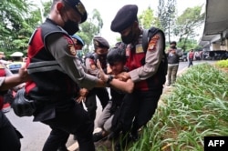 Polisi menangkap seorang pria dalam aksi unjuk rasa di Jakarta, 11 April 2022. (Foto: ADEK BERRY/AFP)