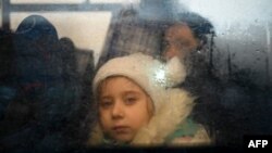 FILE - A girl fleeing the conflict in Ukraine looks on from inside of a bus heading to the Moldovan capital Chisinau, after crossing the Moldova-Ukraine border checkpoint near the town of Palanca, March 2, 2022.