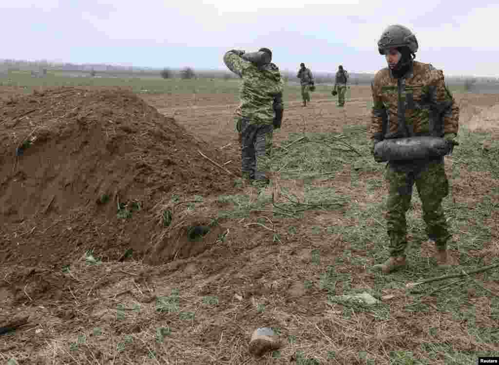 Los zapadores militares llevan proyectiles sin explotar que quedaron después de la invasión de Rusia cerca de la aldea de Motyzhyn, en la región de Kiev, Ucrania, el 10 de abril de 2022.