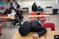Seorang murid beristirahat di mejanya di sebuah sekolah di California (dok: AP/Damian Dovarganes)
