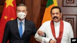 Chinese Foreign Minister Wang Yi, left, poses for media before his meeting with Sri Lankan Prime Minister Mahinda Rajapaksa in Colombo, Sri Lanka, Jan. 9, 2022.