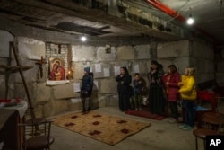 10-year-old Rostyslav Borysenko, who fled besieged Mariupol, left, and displaced children make prayers with nuns at the Hoshiv Women Monastery, April 6, 2022. (AP Photo/Nariman El-Mofty)