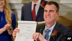 Oklahoma Gov. Kevin Stitt shows his signature on a bill that makes it a felony to perform an abortion, punishable by up to 10 years in prison, in Oklahoma City, Apr. 12, 2022.