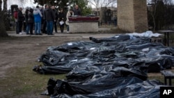 A family mourns a relative killed during the war with Russia, as dozens of black bags containing more bodies of victims are seen strewn across the graveyard in the cemetery in Bucha, in the outskirts of Kyiv, Ukraine, April 11, 2022.