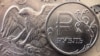 FILE - A Russian ruble coin is pictured with U.S. currency in Moscow, March 15, 2022.
