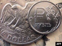 FILE - A Russian ruble coin is pictured with U.S. currency in Moscow, March 15, 2022.