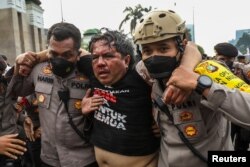 Ade Armando, dosen dan aktivis sosial, diselamatkan oleh petugas polisi setelah terluka akibat dikeroyok massa dalam aksi protes di dekat gedung DPR RI di Jakarta, 11 April , 2022. (Antara Foto/Galih Pradipta/ via REUTERS )