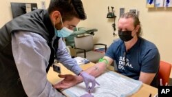 Jacob Marquez, koordinator penelitian klinis di Knight Cancer Institute di Oregon Health & Science University di Portland, mengambil darah peserta studi klinis David Parker pada 14 Maret 2022. (Foto: AP)
