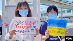 兩名大專女生化名阿貓(左）及H同學手持標語參與快閃反戰示威，要求俄羅斯停止入侵烏克蘭。(美國之音/湯惠芸)