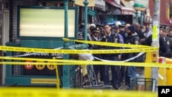 Polisi New York berkumpul di pintu masuk halte kereta bawah tanah (subway) di wilayah Brooklyn, New York, Selasa, 12 April 2022. Beberapa orang terluka akibat serangan pada jam sibuk pagi hari, di stasiun kereta bawah tanah di New York City. (AP/John Minchillo)